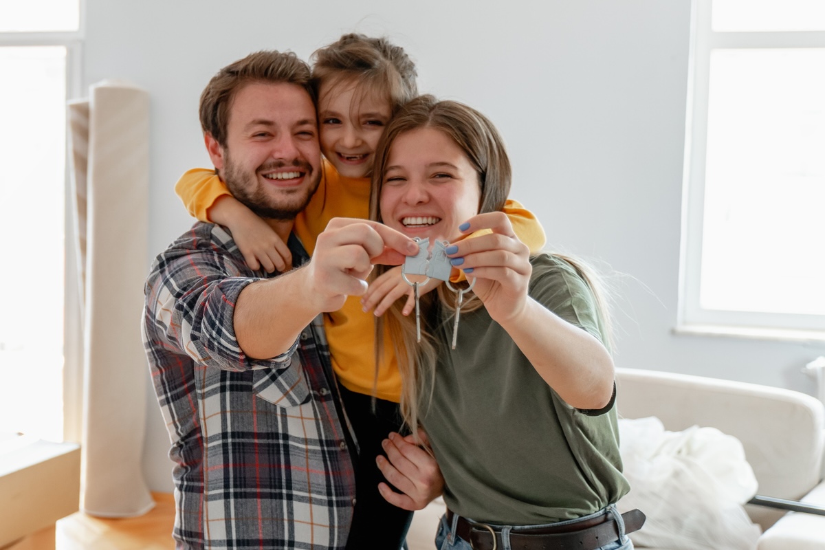 Ein Mann sitzt am Schreibtisch und betrachtet Baupläne sowie ein 3D‑Modell einer Immobilie auf seinem Laptop.